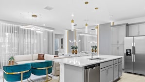 A modern kitchen with a central island, stainless steel appliances, and a dining area with a sofa and chairs.