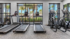 Un gimnasio con cintas de correr, elípticas y bicicletas estáticas.