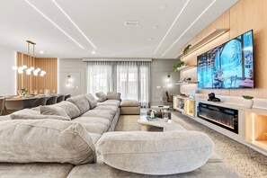Relax in this spacious living room with a luxurious sectional sofa inviting you to unwind. Natural light pours in through large windows, accentuating the warm wood details and modern decor for a truly welcoming atmosphere.