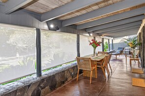 Un amplio espacio interior con una larga mesa y sillas, un muro de piedra y ventanas grandes con vistas a zonas verdes.