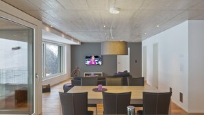 A modern interior with a dining area, a sofa set, and a television mounted on the wall.
