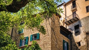 A stone building with green shutters and balconies.