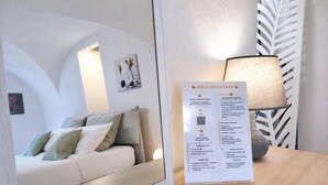 A hotel room with a bed, a bedside table with a lamp, and a wall-mounted information board.