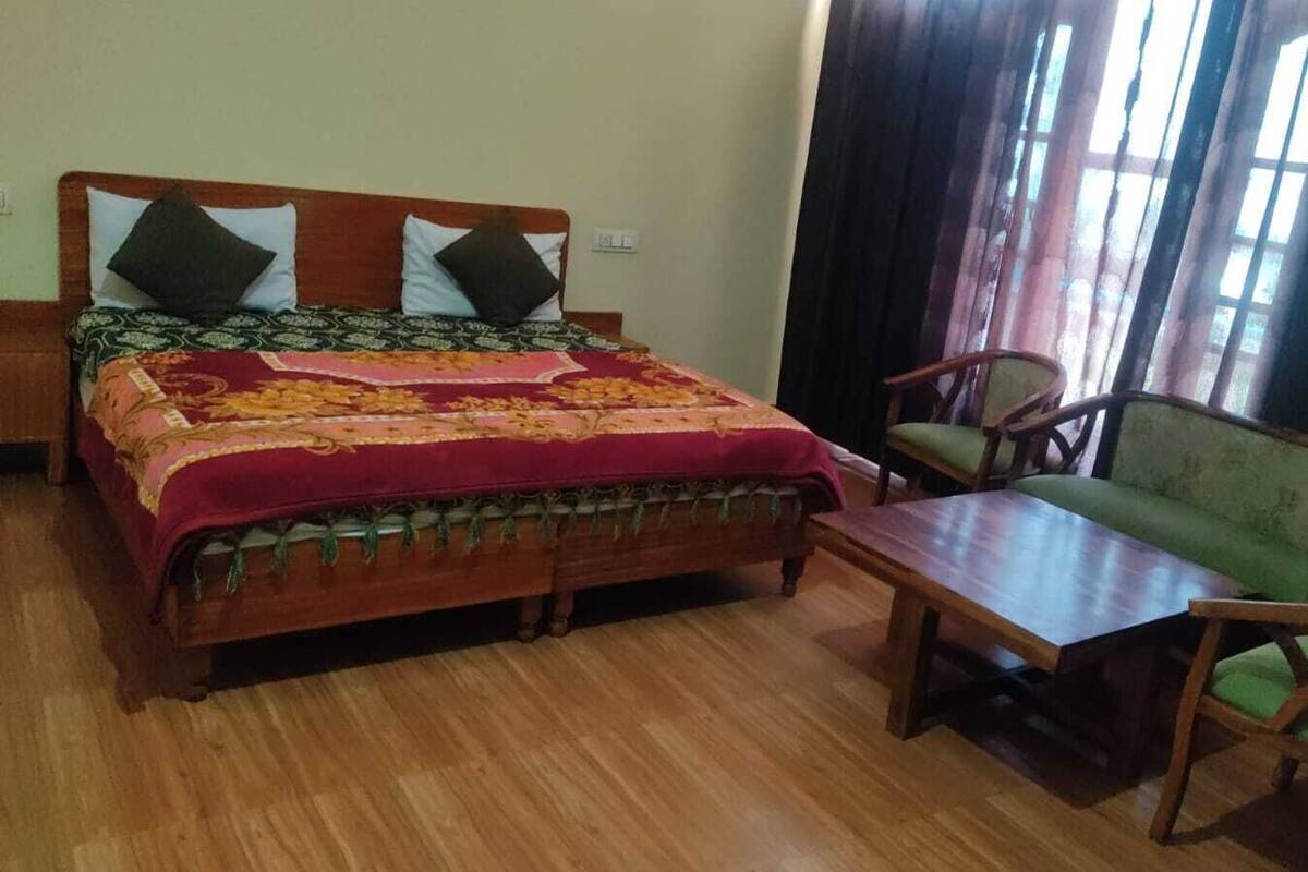 Ein Zimmer mit einem hölzernen Bett, einem grünen Sofa und einem Holztisch.