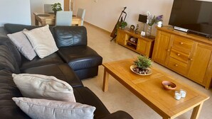 A living room with a black leather sofa, a wooden coffee table, and a television on a wooden cabinet. - **Introductory Discount** Gorgeous Apartment with Golf & Pool Views 14132 (Torre-Pacheco)