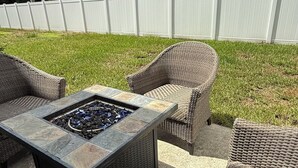 Eine Terrasse im Freien mit Korbmöbeln und einem Steinkamin.