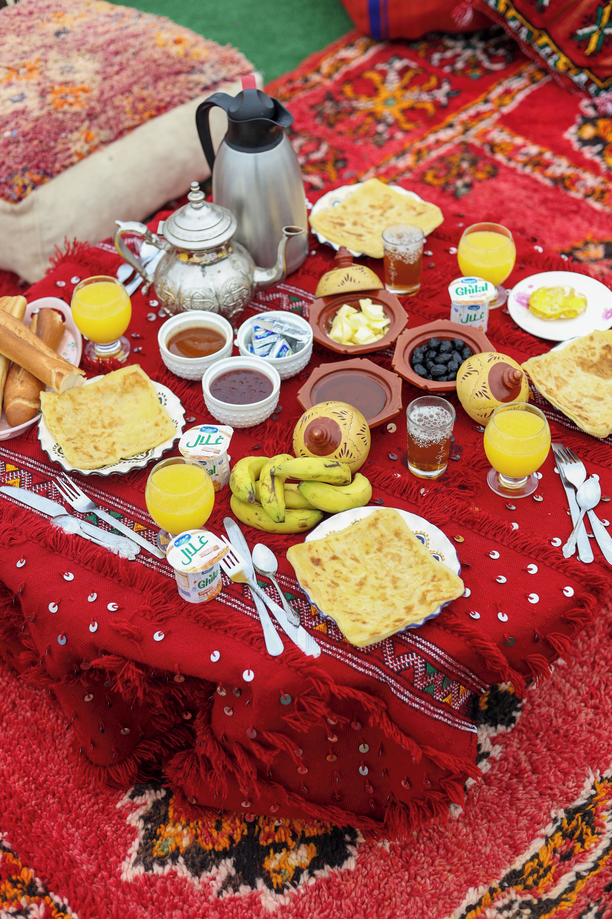 Una mesa preparada con diversos alimentos para el desayuno, como pan, plátanos y bebidas.