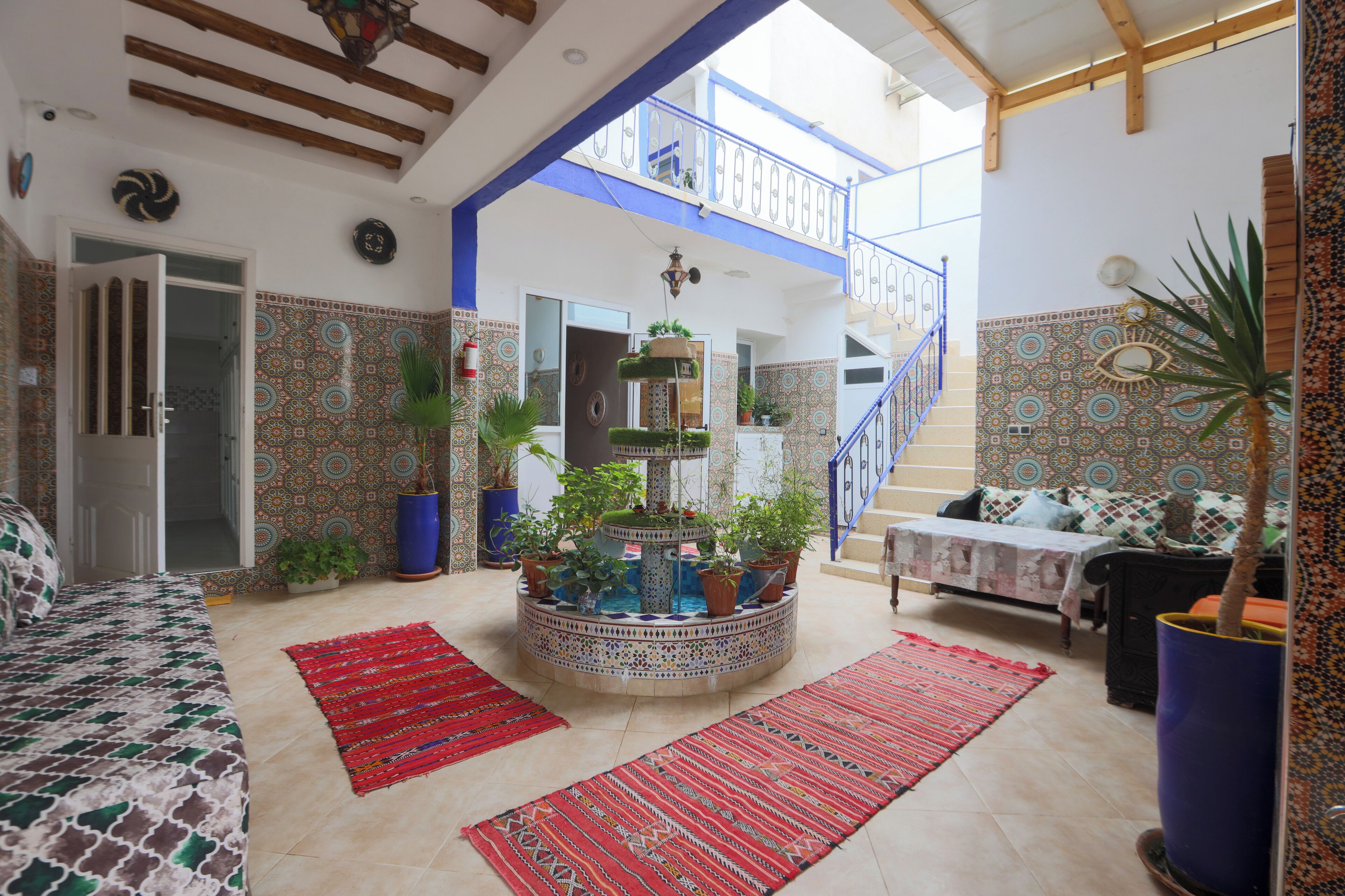 A spacious living area with a high ceiling, a central fountain, and a staircase leading to an upper level.