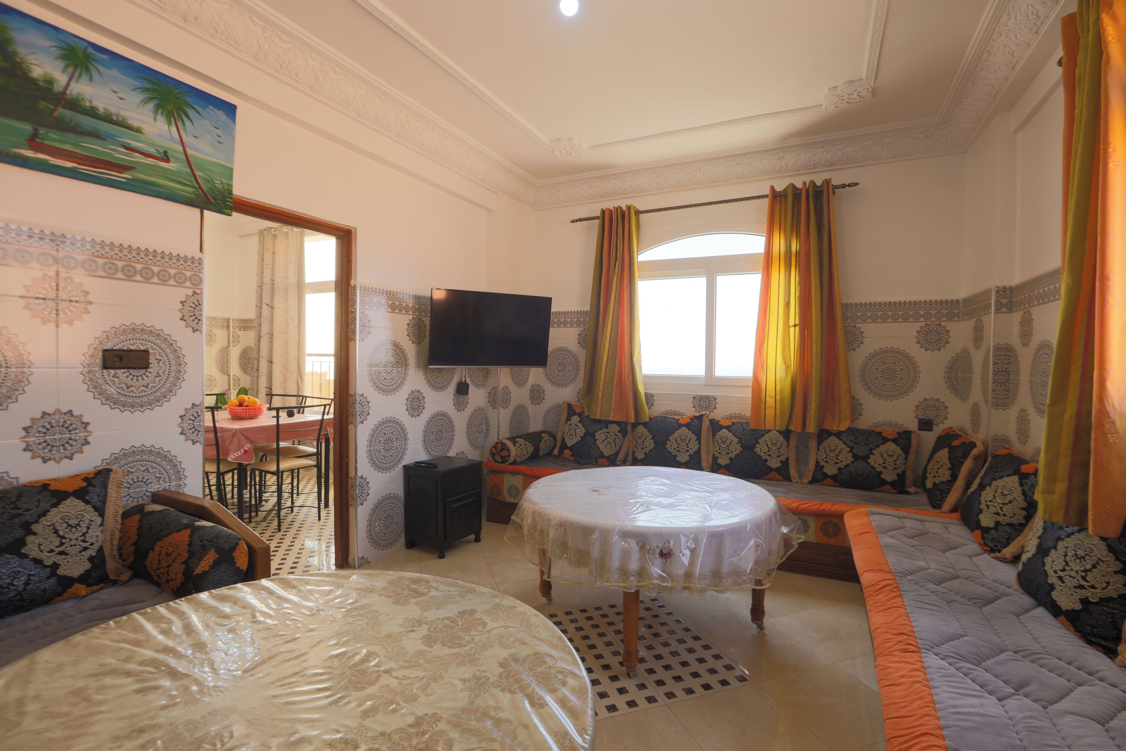 A room with a sofa, a round table, a TV, and patterned walls.