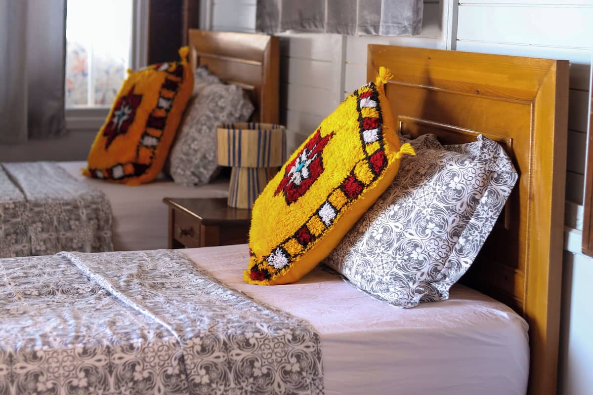 Un dormitorio con cabecera de madera, ropa de cama estampada y almohadas decorativas.