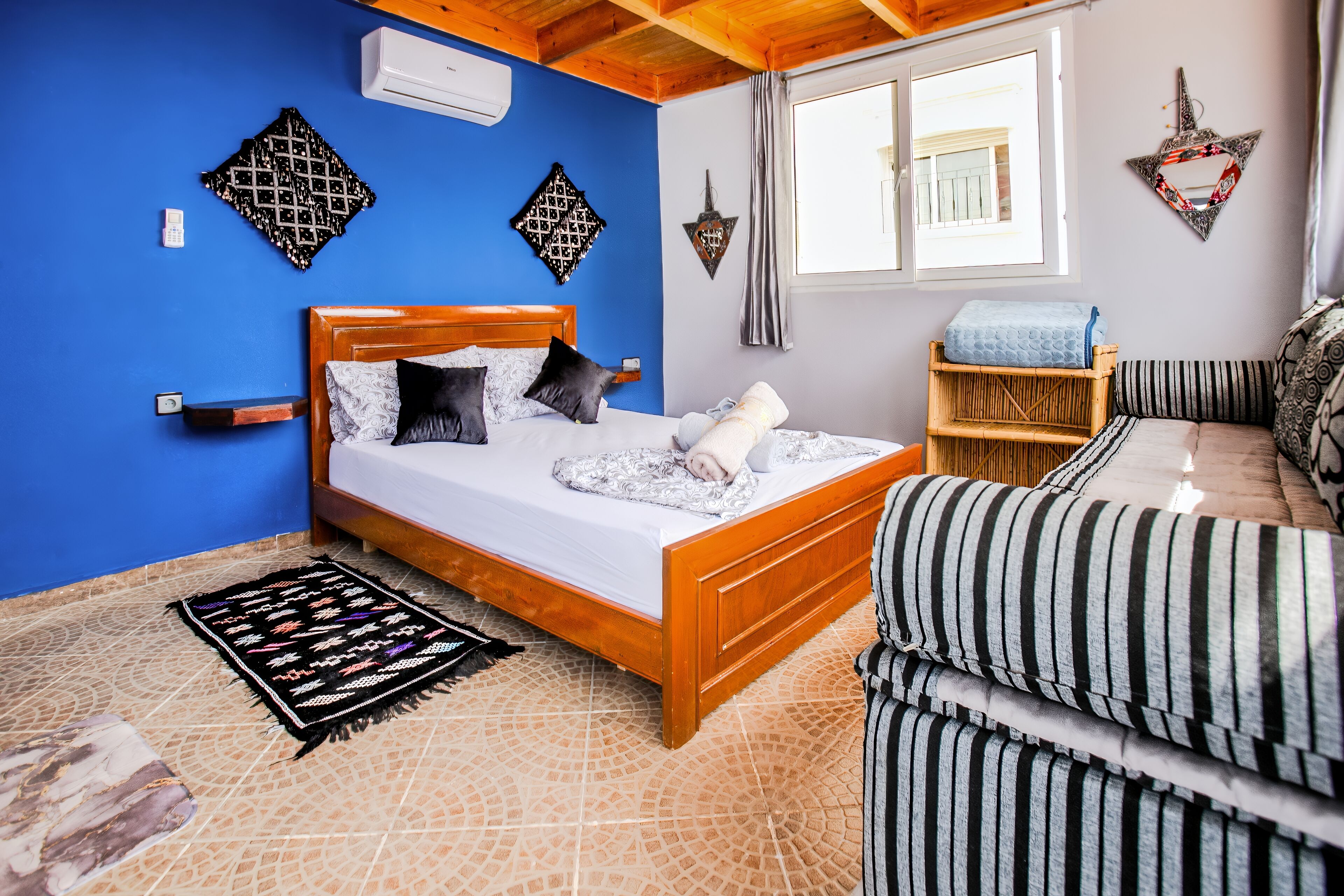 Une chambre à coucher avec un lit en bois, un mur bleu et une fenêtre.