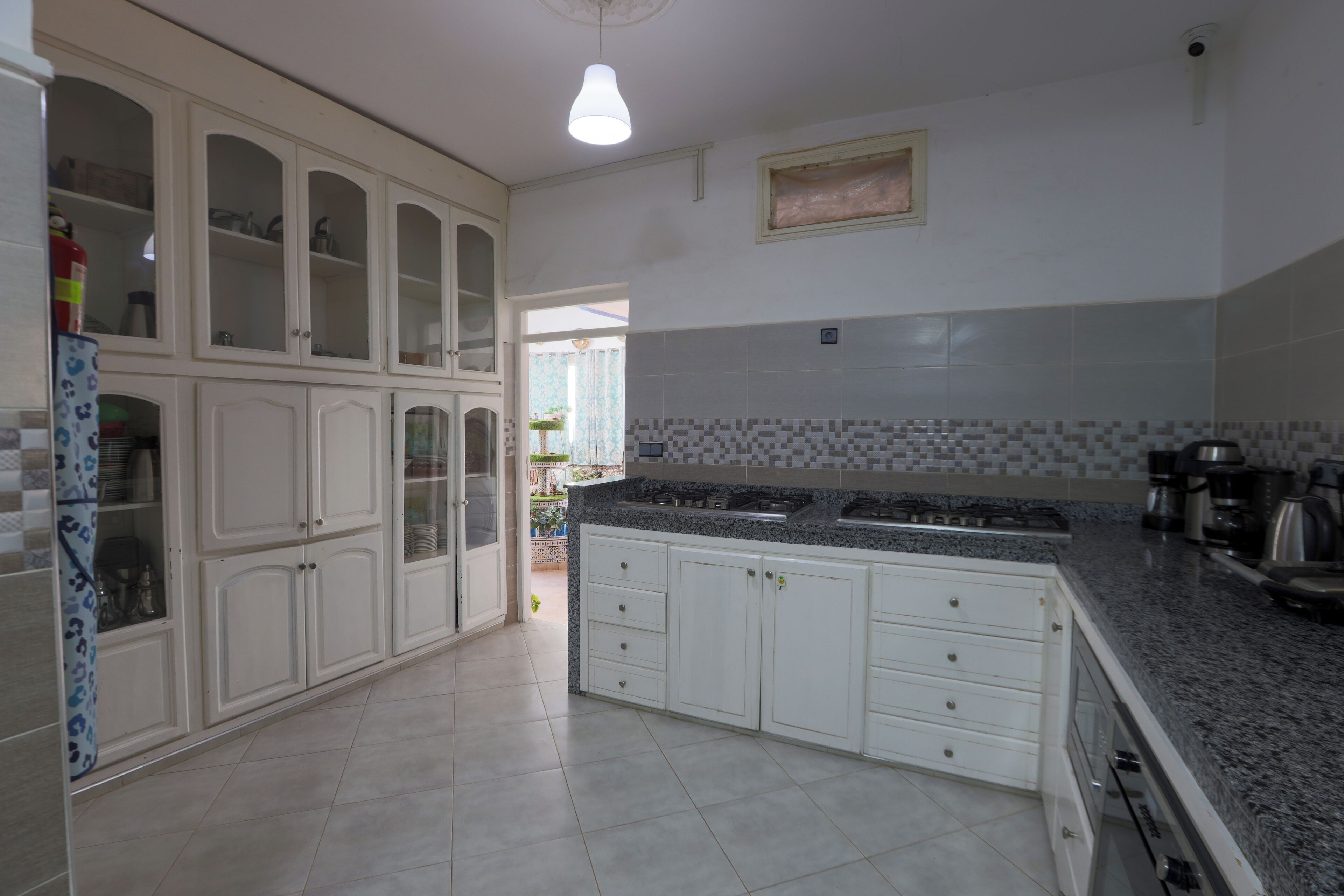A kitchen with white cabinets, a granite countertop, and a tiled backsplash.