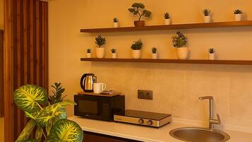 A modern kitchen with a round dining table, a potted plant, a coffee maker, a microwave, a toaster, and a stainless steel sink.