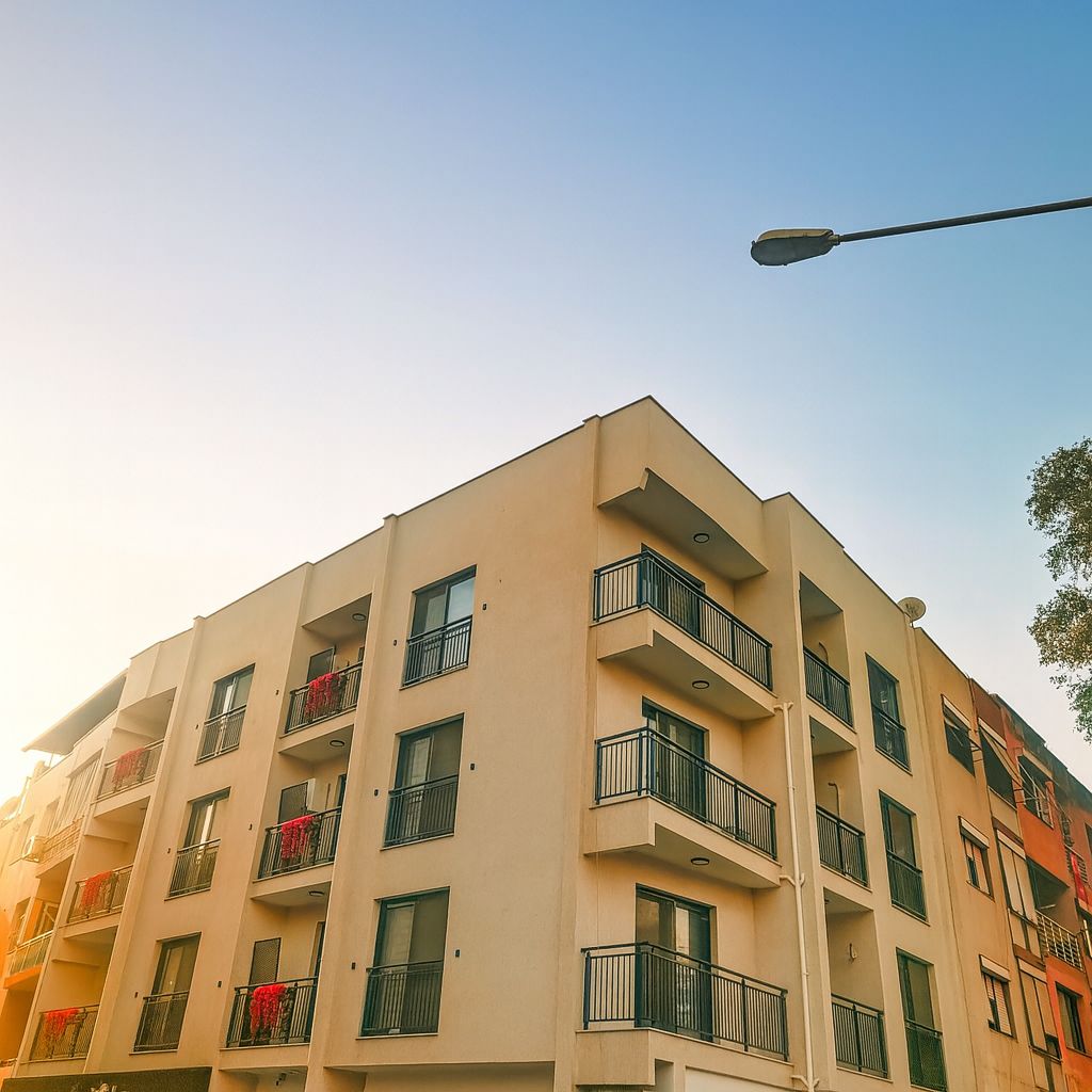 Un immeuble à plusieurs étages doté de balcons, d’un toit plat et d’un lampadaire.