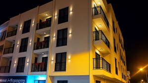 Et hotel med flere etager, altaner, oplyste vinduer og en tydelig butiksetage.