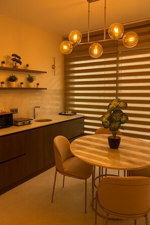 A modern kitchen with a round dining table, two chairs, and a potted plant. - Elegant Ephesus Suites - Artemis (İzmir)