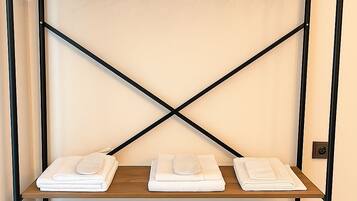 A metal rack with multiple shelves and hooks, with folded white towels on the bottom shelf.
