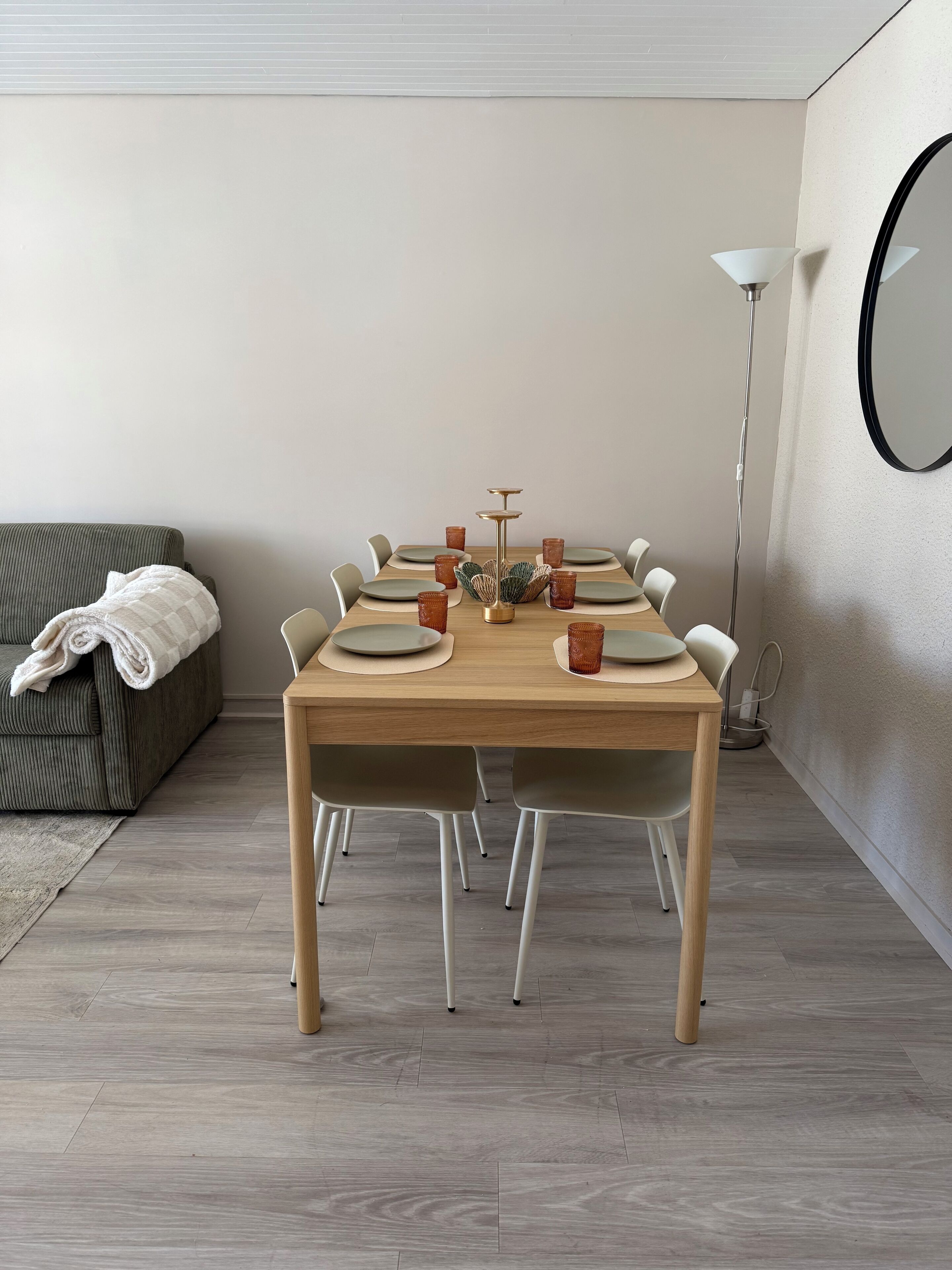 Een eetruimte met een houten tafel gedekt voor zes personen, omringd door stoelen.