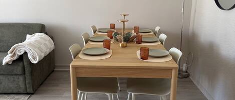 Een eetruimte met een houten tafel gedekt voor zes personen, omringd door stoelen.