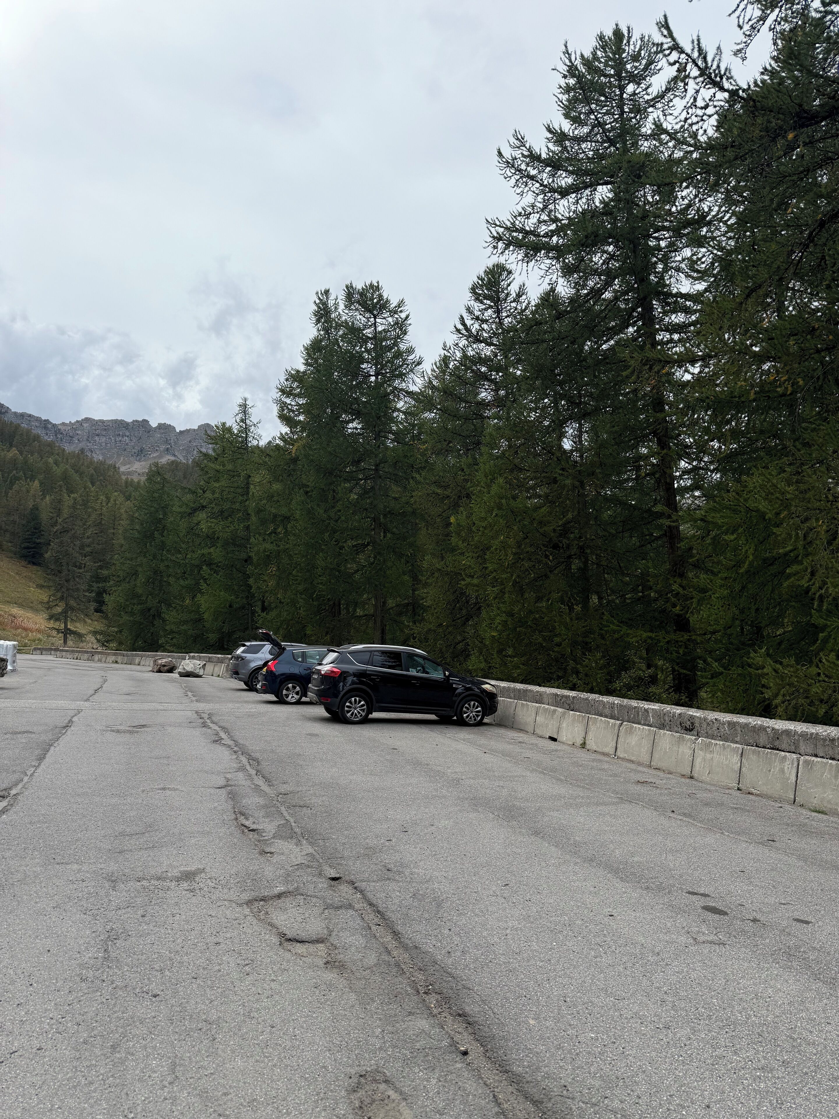 A parking area with vehicles and a concrete barrier.