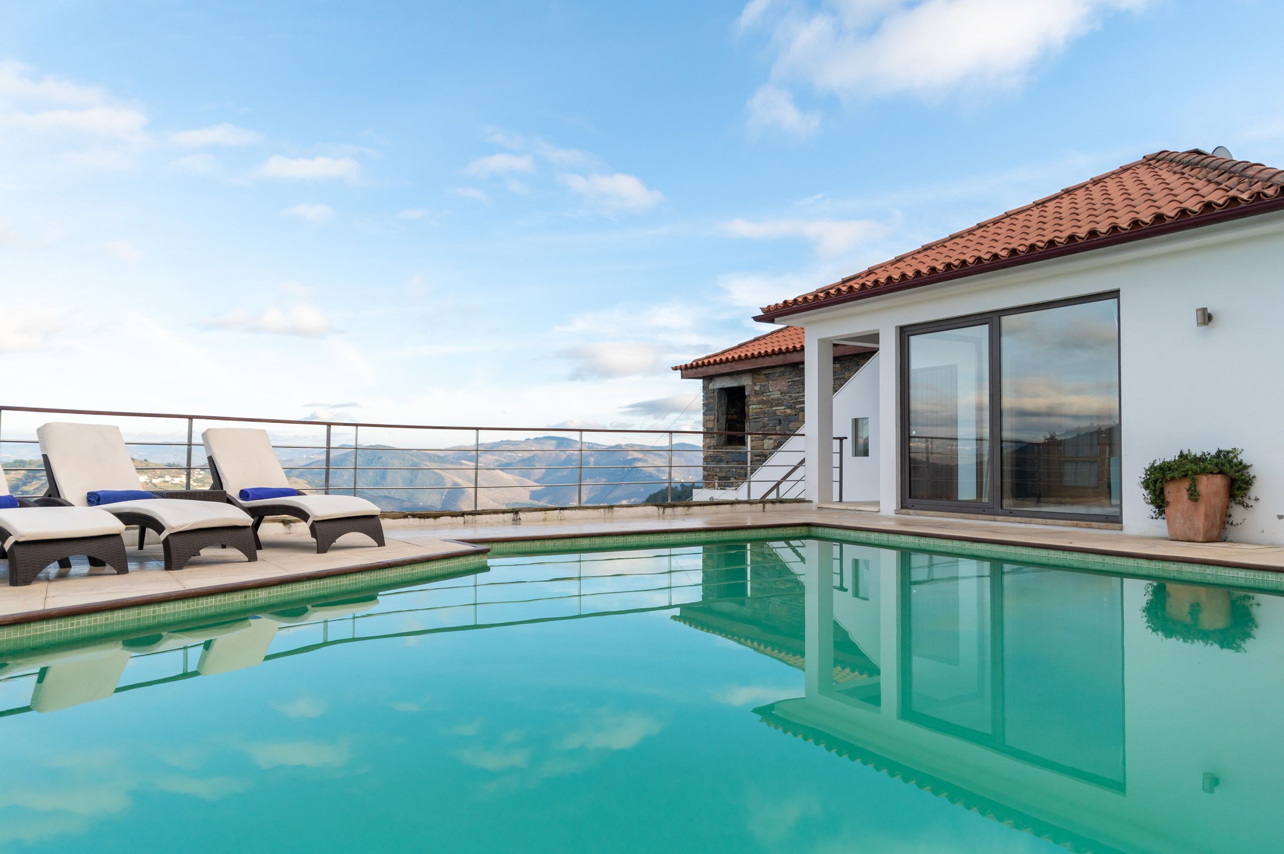 Zona junto a la piscina con sillones de descanso y vistas a las montañas.