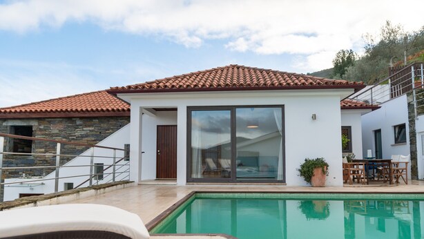 Et moderne hus med swimmingpool, stentrappe og en terrasse med udendørs møbler.