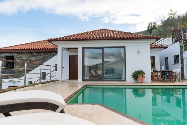 A modern house with a swimming pool, stone staircase, and a patio with outdoor furniture.