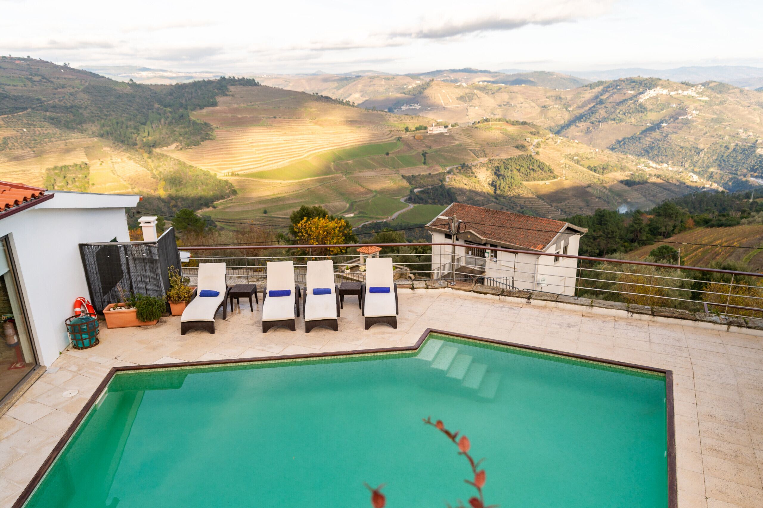 Una piscina con sillones de descanso y vistas a colinas onduladas.