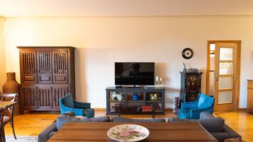 Una sala de estar con un aparador de madera, un televisor y dos sillones azules.