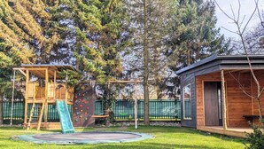 Une aire de jeux avec un toboggan, un mur d’escalade et des balançoires.