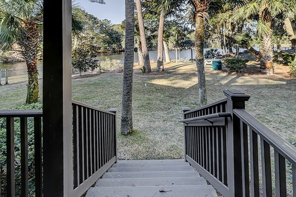 A staircase leading to a grassy area with palm trees and a body of water in the background.