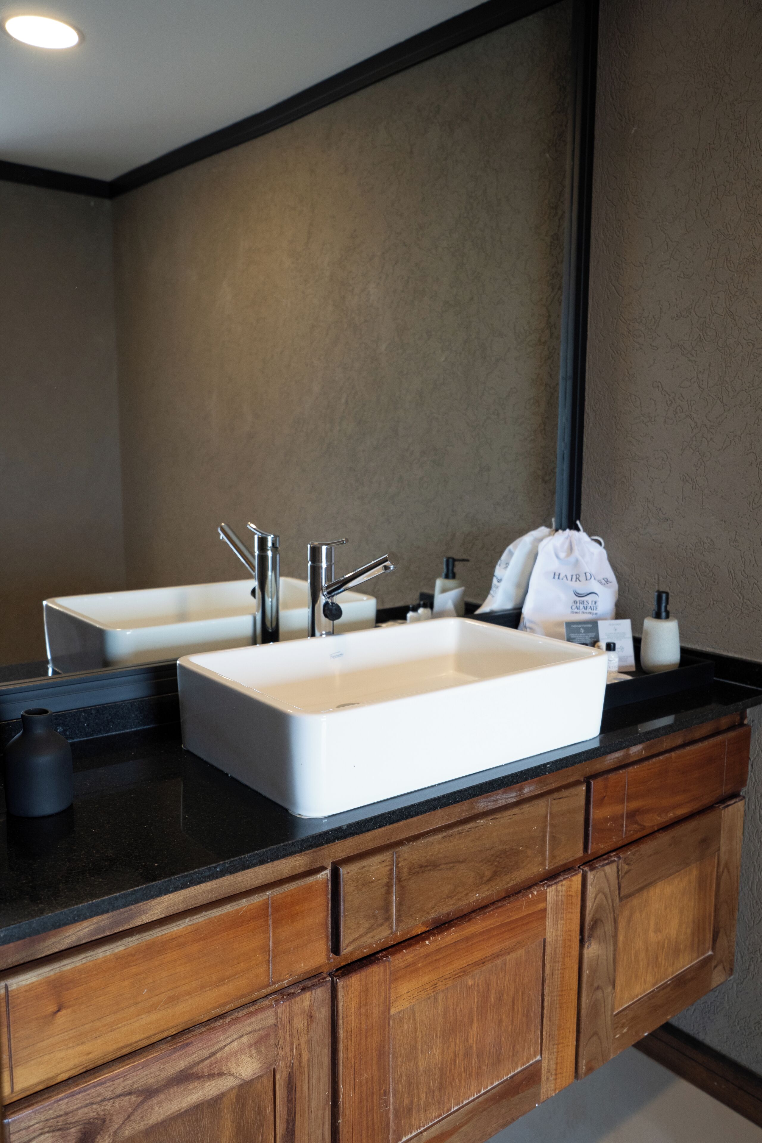 A bathroom with two sinks, a mirror, and wooden cabinetry.
