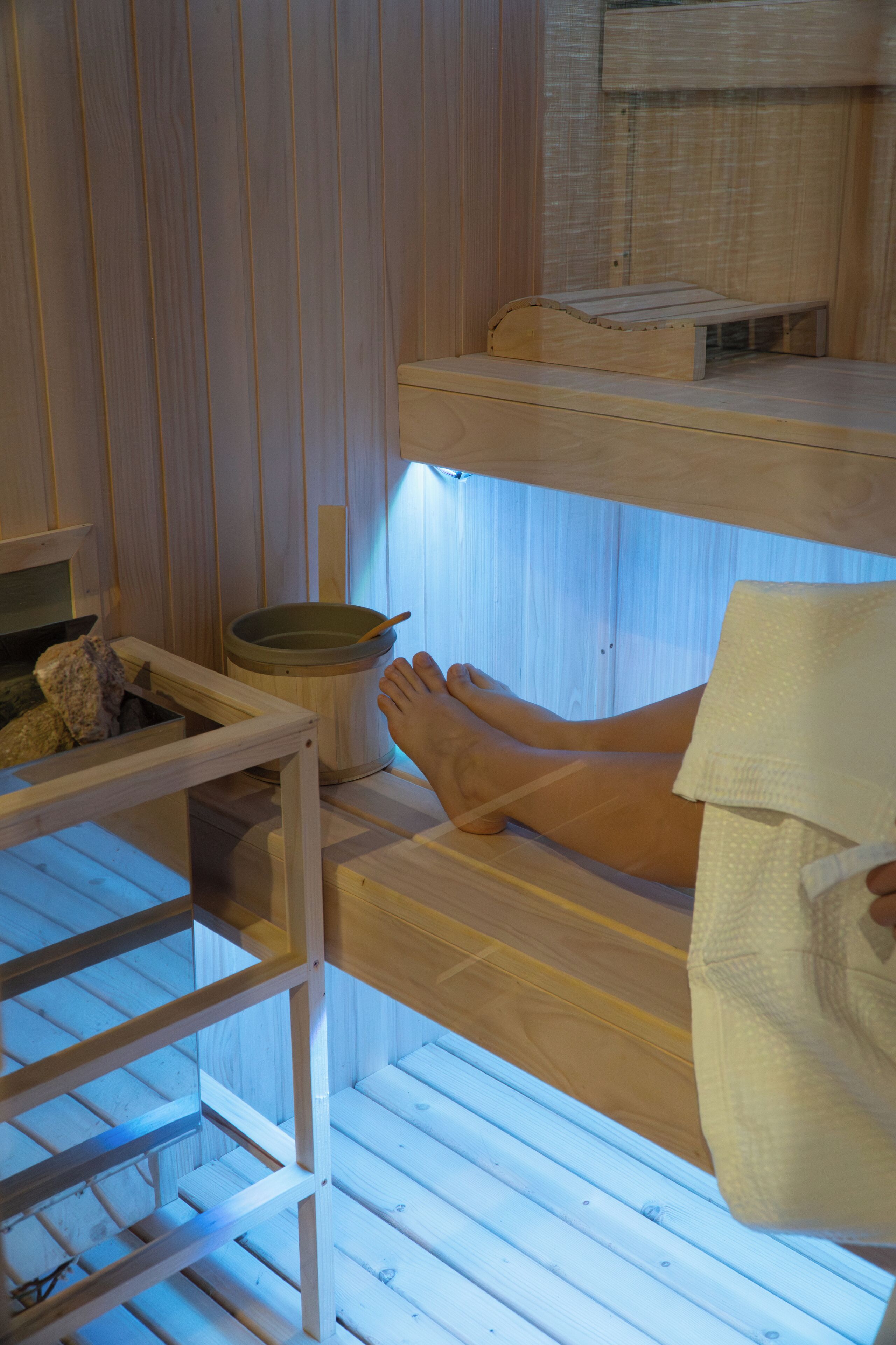 Una sauna de madera con bancos y un balde de madera.