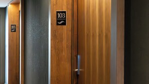 A hallway with wooden doors, numbered signs, and a tiled floor. - Hotel Ayres de Calafate (El Calafate)