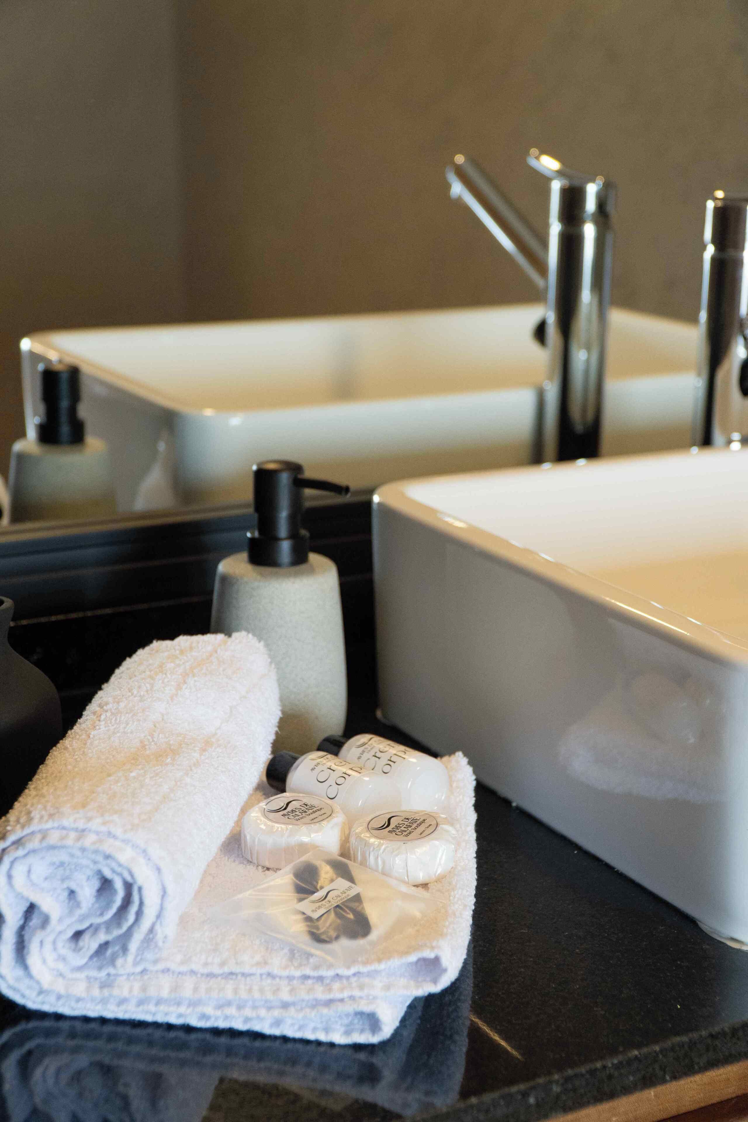 Ein Badezimmer mit einem großen Spiegel, zwei Waschbecken, einem Handtuch und Toilettenartikeln.