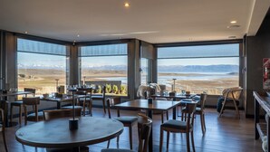 A modern dining area with large windows offering a mountain view. - Hotel Ayres de Calafate (El Calafate)