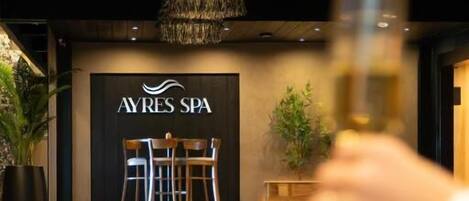 A spa area with a sign reading 'AYRES SPA,' a pool, and a table with chairs.