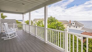 A covered porch with white railings and a rocking chair.