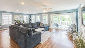 A spacious living room with a grey sectional sofa, a white coffee table, and a ceiling fan.