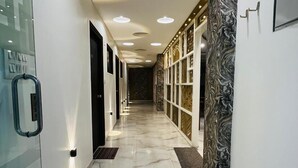A modern hallway with marble flooring, recessed ceiling lights, and a glass door with a handle.