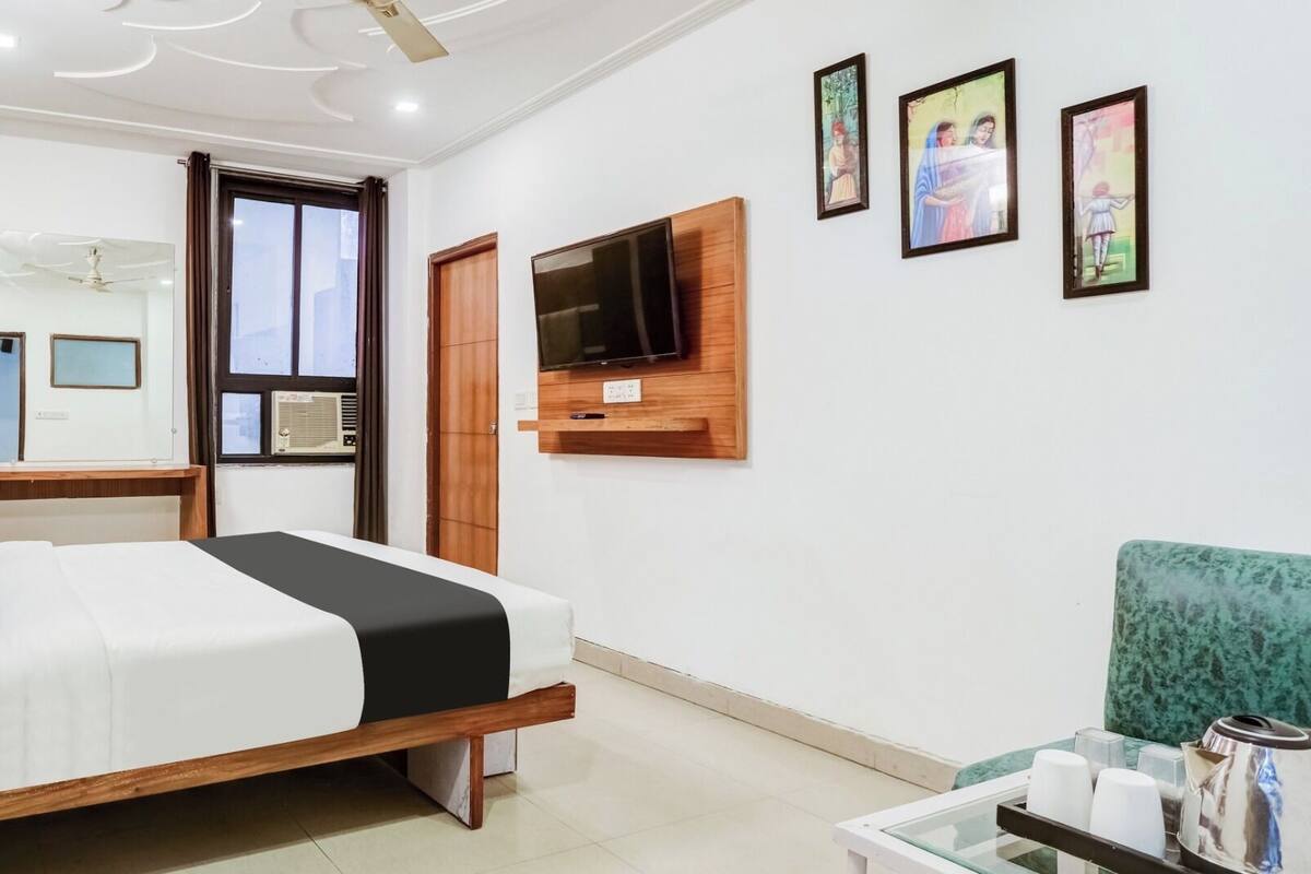 Une chambre d’hôtel avec un lit, un téléviseur fixé au mur et trois tableaux encadrés.