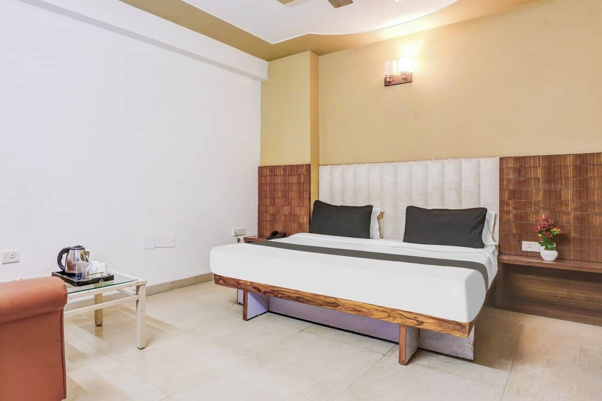 Une chambre à coucher avec un lit, une table de chevet et une petite table sur laquelle se trouvent une bouilloire et des tasses.