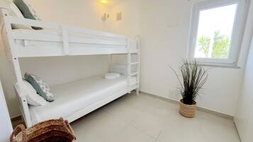 Une chambre avec un lit superposé, une fenêtre et une plante en pot.