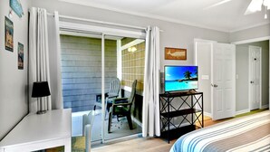 Ein Hotelzimmer mit einem Bett, einem Fernseher, einem Schreibtisch, einem Stuhl und einer Schiebetür zu einem Balkon.