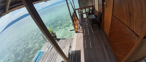 A wooden deck with a view of clear turquoise water and distant mountains.
