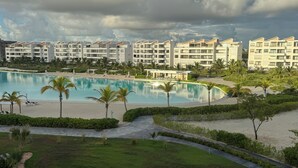 A resort with a swimming pool, palm trees, and a beach. - Chic Boho Apartment Overlooking Crystal Lagoon (Punta Cana)