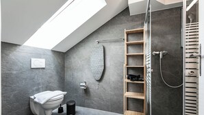 A modern bathroom with a skylight, a shower, a toilet, and a wooden shelf unit. - book2stay 2.5-room apartment #8 Säntis up to 6 people (St. Gallen)