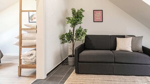 A modern living room with a dark grey sofa, a small potted plant, and a framed sign on the wall. - book2stay 2.5-room apartment #8 Säntis up to 6 people (St. Gallen)