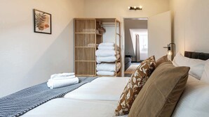 A hotel room with a bed, a bedside table, a wardrobe, and a bathroom visible through an open door. - book2stay 2.5-room apartment #8 Säntis up to 6 people (St. Gallen)