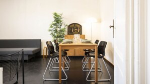 En matplats med ett träbord, fyra stolar, en krukväxt och en skylt med texten ”Här serveras god mat på mässan”.
